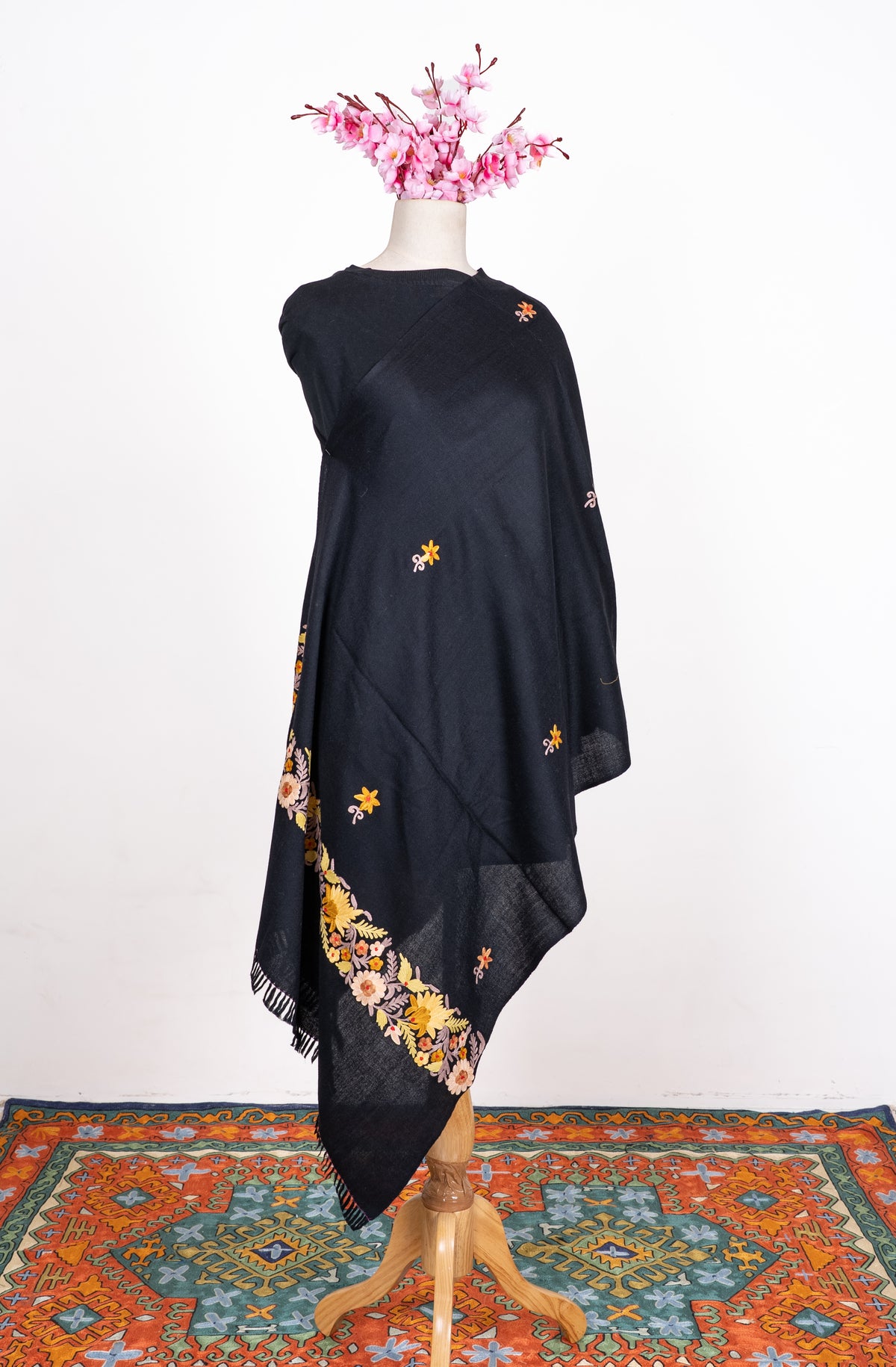 Full view of the black shawl on a mannequin, with scattered small Aari flowers and a cream and yellow floral end border