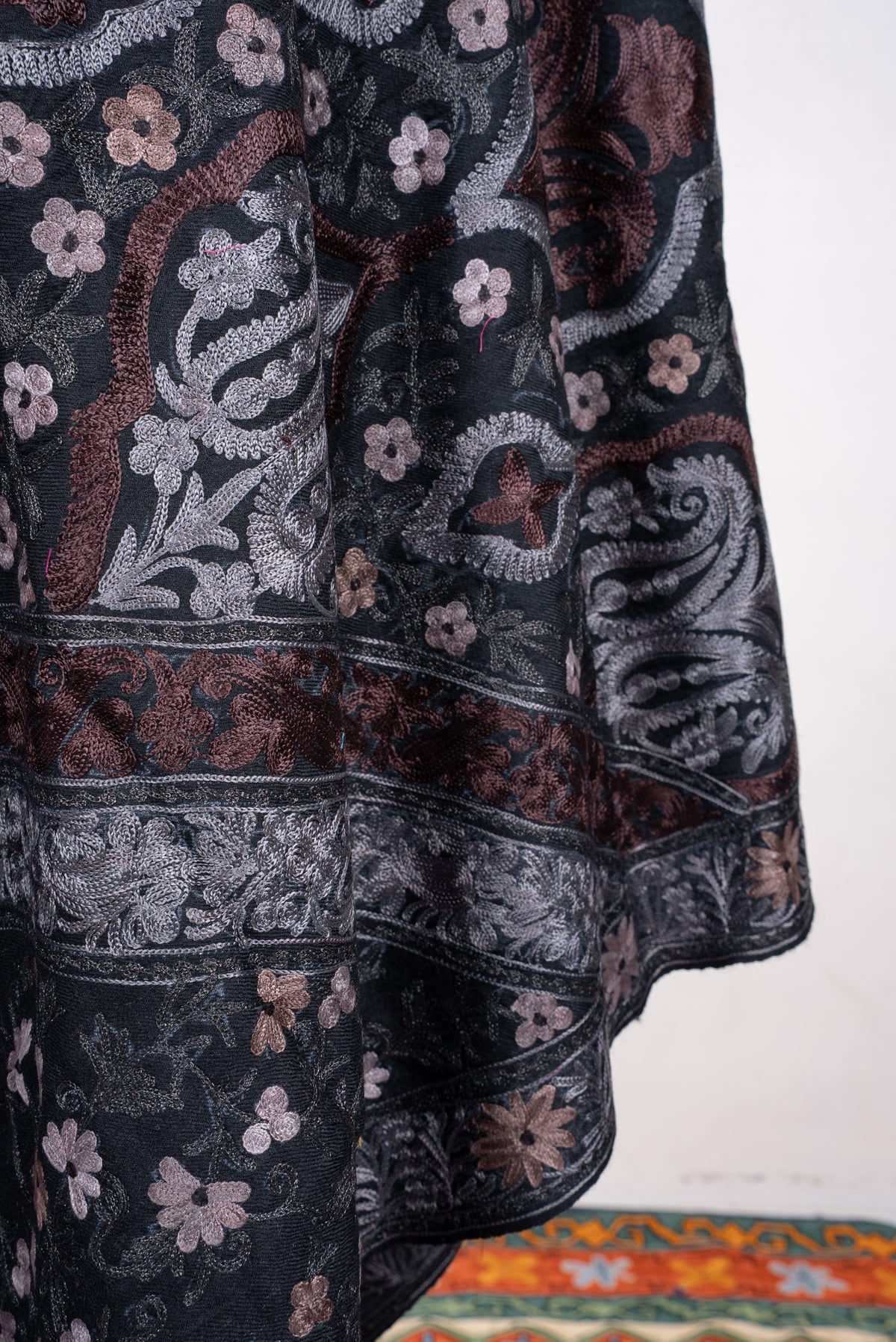Close-up of black shawl folds with silver and muted-rose paisleys, small flowers and layered embroidered borders