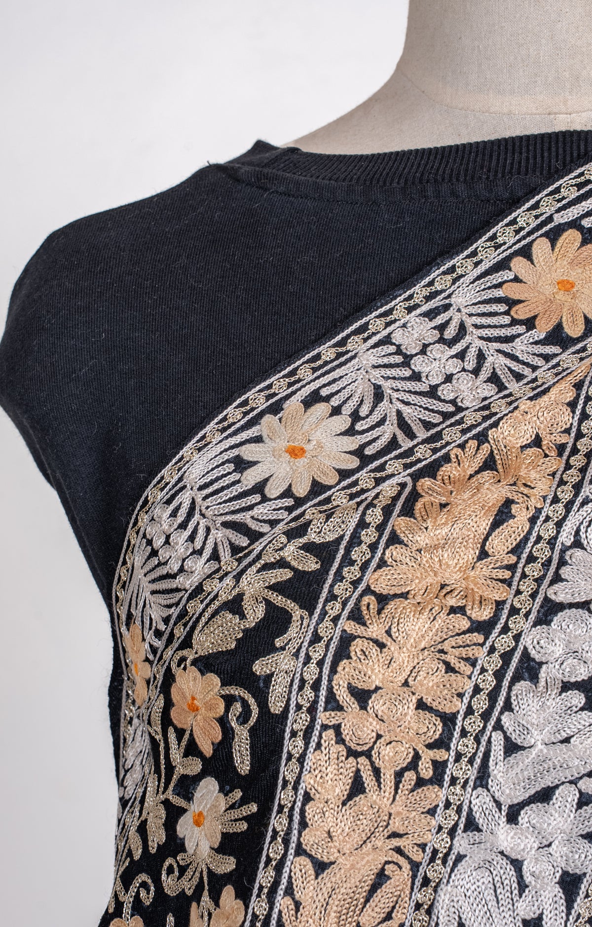 Shoulder close-up of the black shawl, showing ivory and gold-toned Aari flowers and densely stitched leafy borders