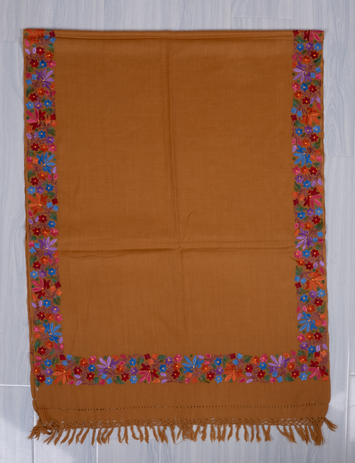 Mustard shawl spread flat, with a plain field framed by bright multicoloured Aari floral borders and a fringed end