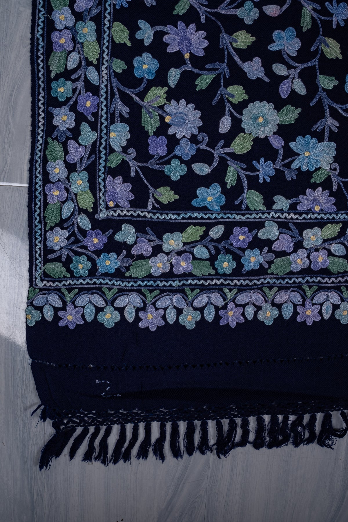 Flat corner detail of the sapphire shawl, with blue and lavender Aari flowers, mint leaves and layered borders above fringe
