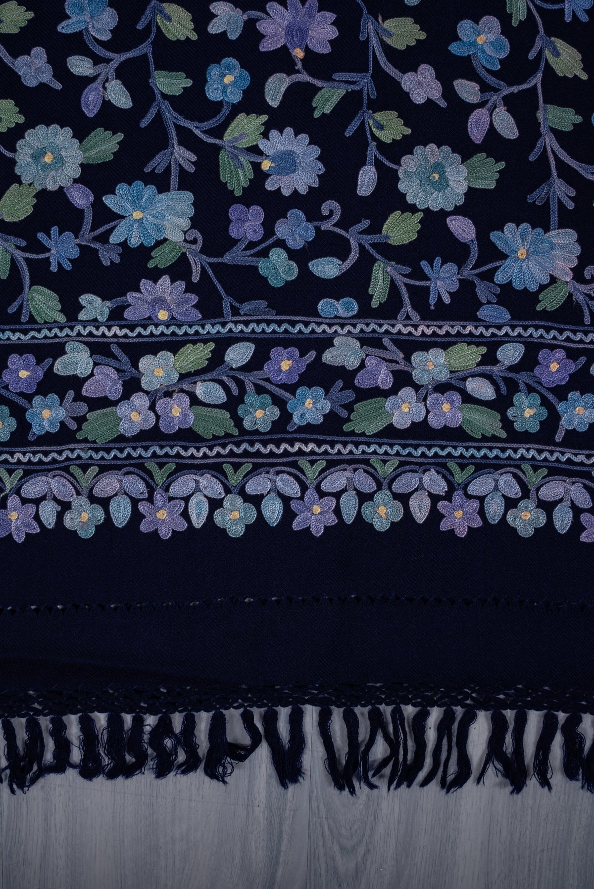Flat end detail of the sapphire shawl, showing pastel Aari flowers, layered floral borders and dark blue fringe