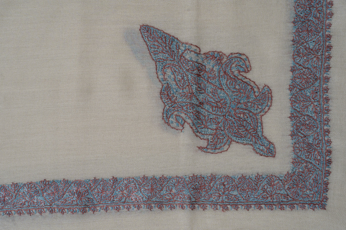 Ivory rumal corner with an ornate turquoise and coral Sozni floral motif inside narrow borders