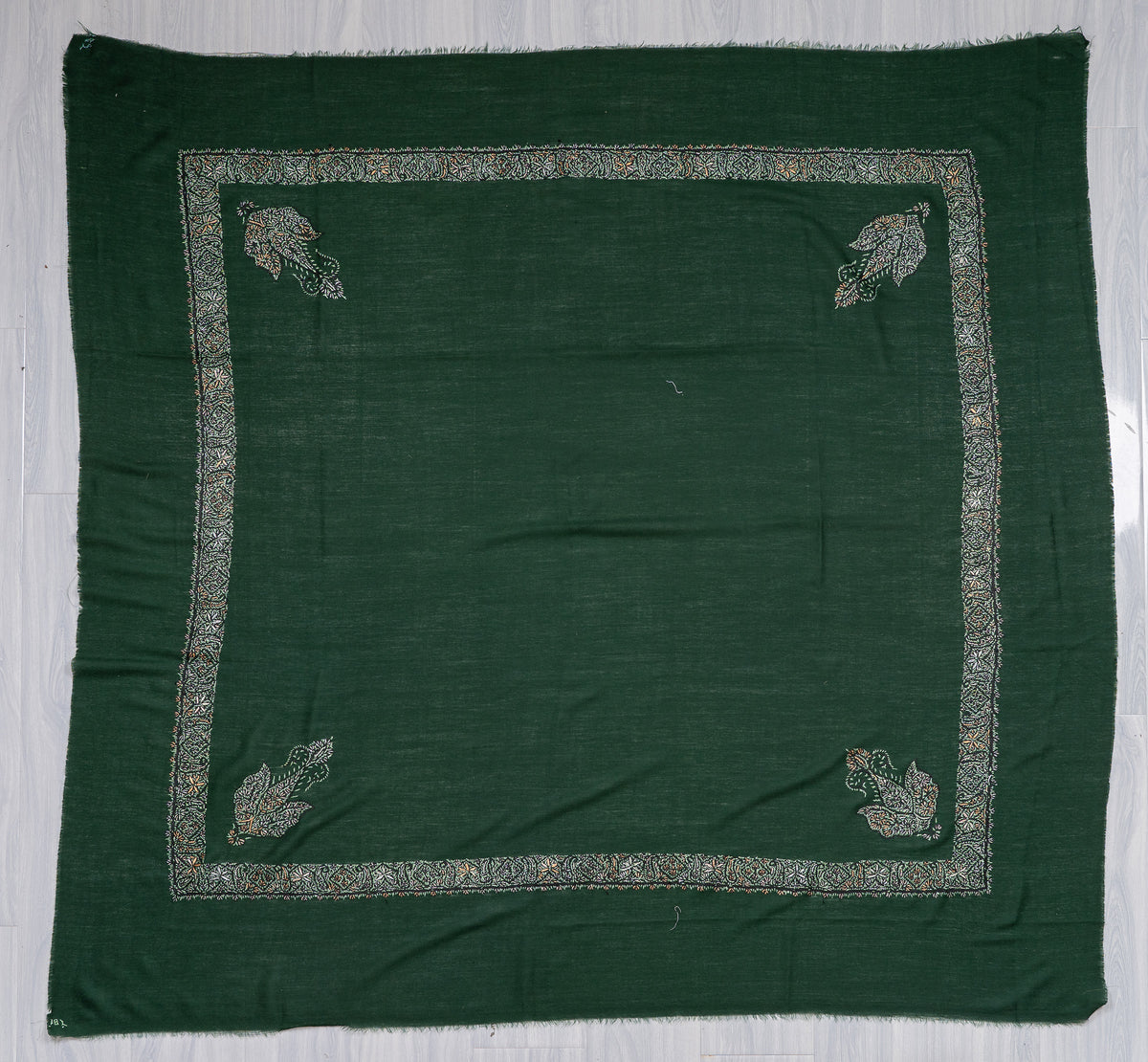Square dark green Merino wool rumal laid flat, with a pale floral border and four paisley corner motifs