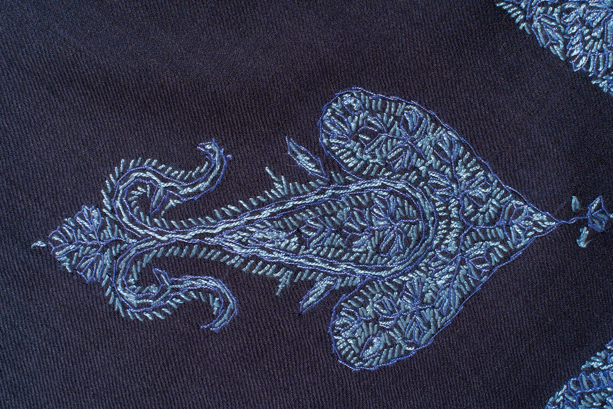 Detail of an icy blue paisley-floral corner motif filled with fine leaves on dark navy fabric