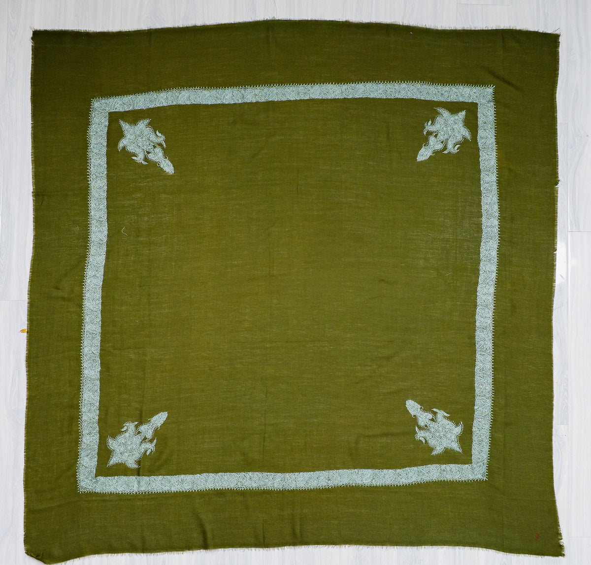 Square olive-green Merino wool rumal laid flat with pale blue Sozni borders, four corner paisleys and a plain centre