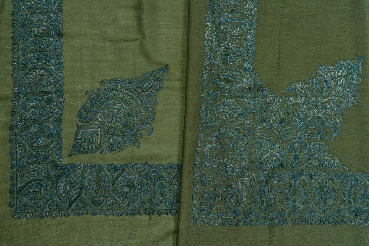 Folded olive rumal showing two contrasting teal corner motifs and overlapping embroidered borders