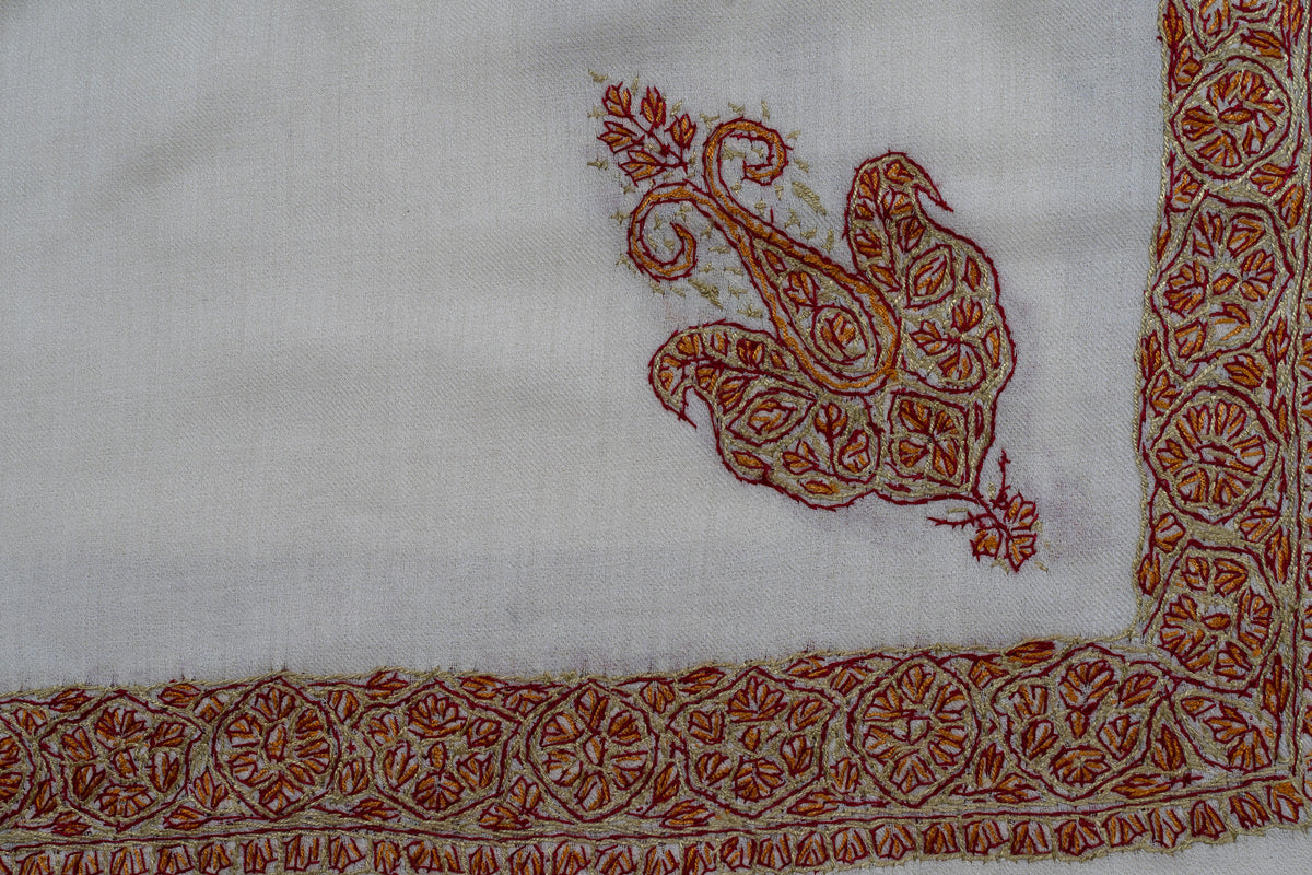 Ivory rumal corner with a rust and gold Sozni motif inside narrow floral borders