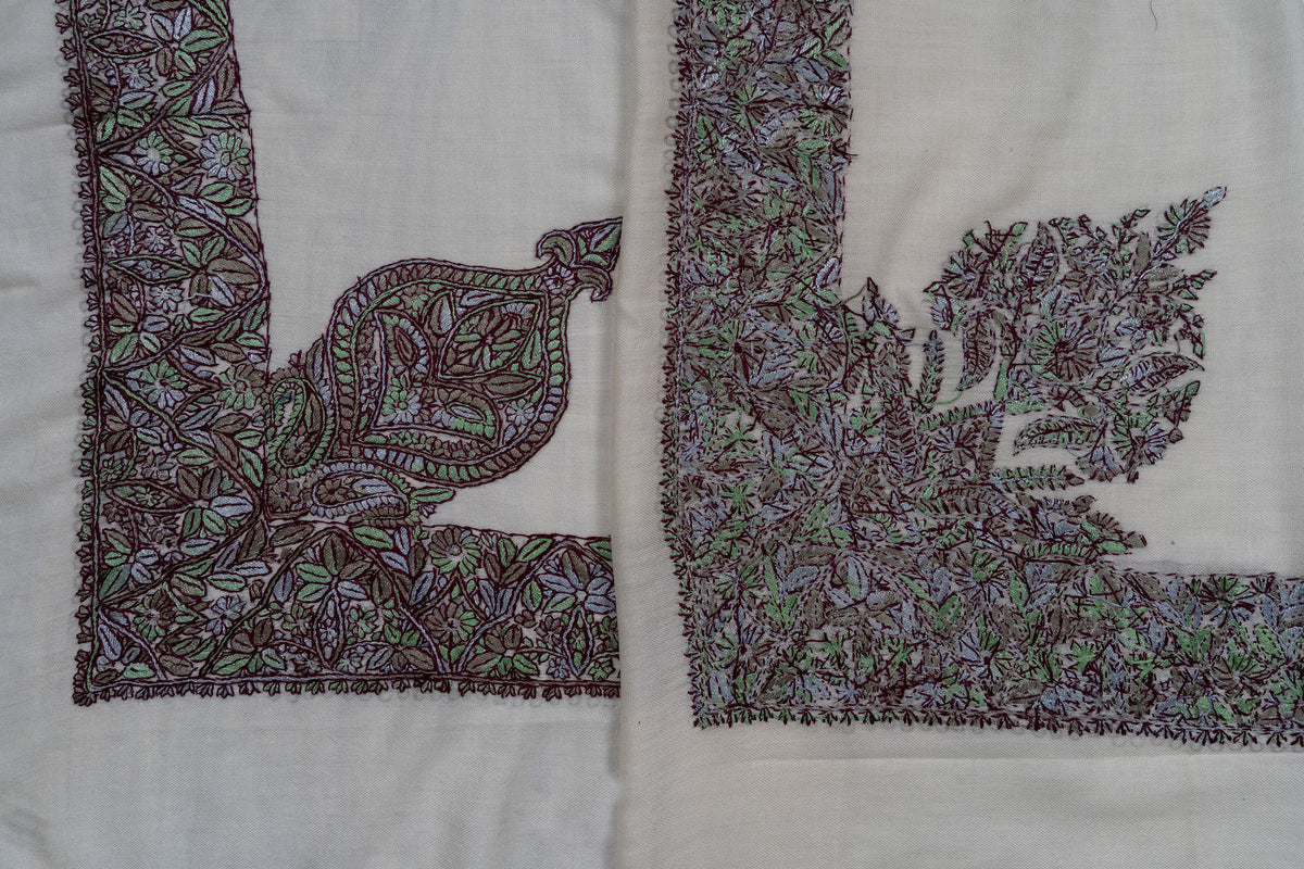 Folded ivory rumal showing the front and reverse of purple-and-green floral embroidery and contrasting corner motifs