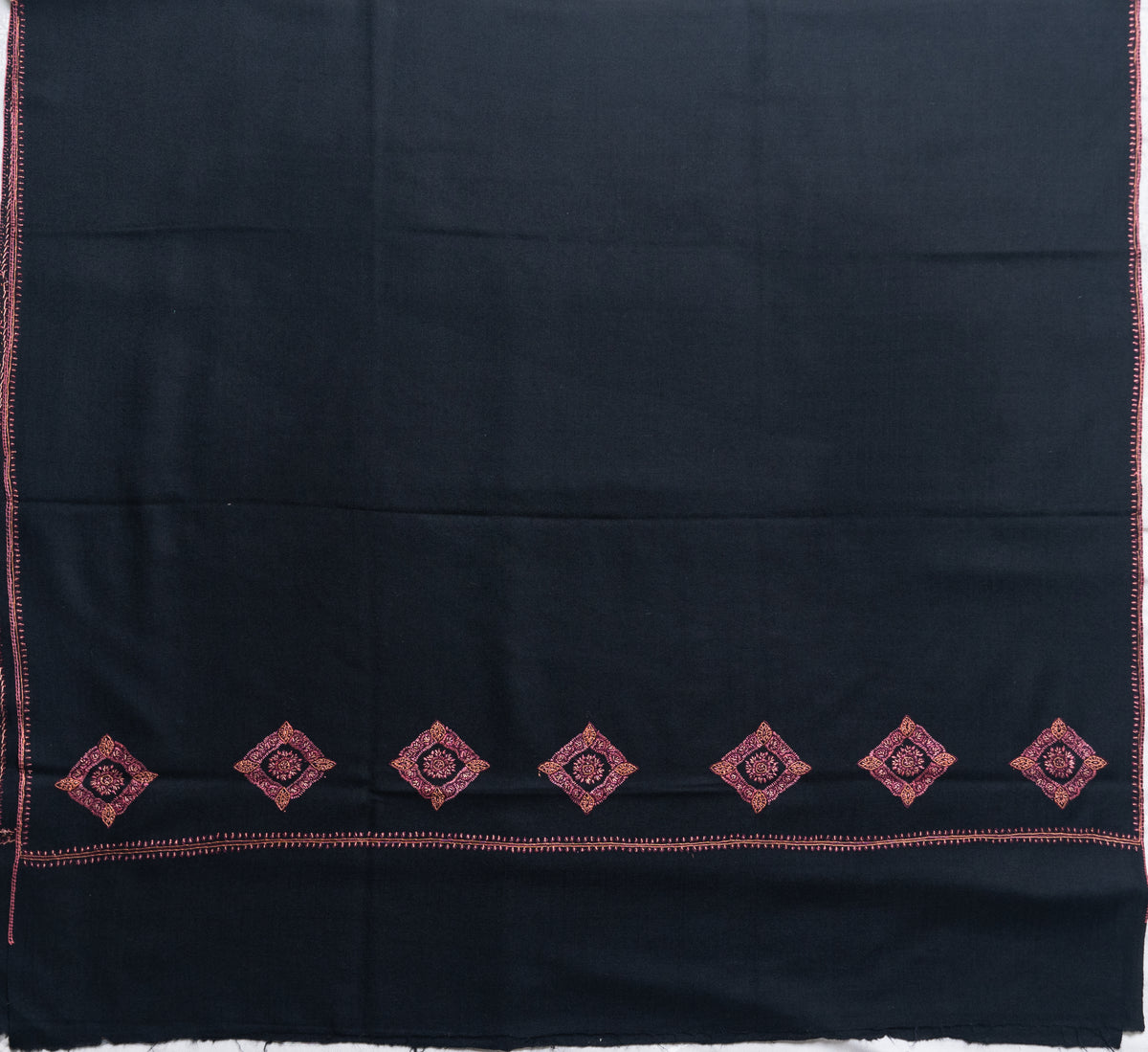 Black shawl laid flat with a row of red diamond-shaped floral motifs across the end and fine embroidered side borders.