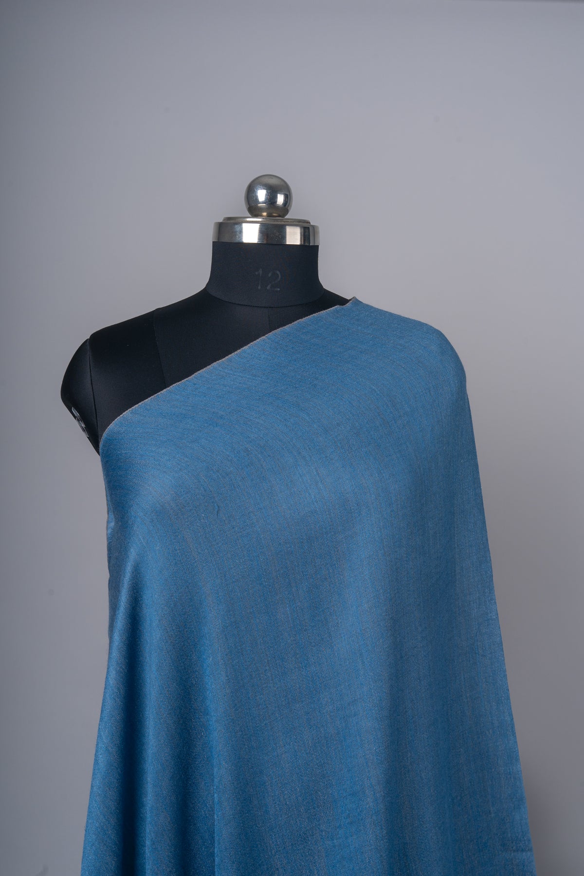 Upper drape of the plain azure-blue stole, showing its fine woven texture across the mannequin’s shoulder.
