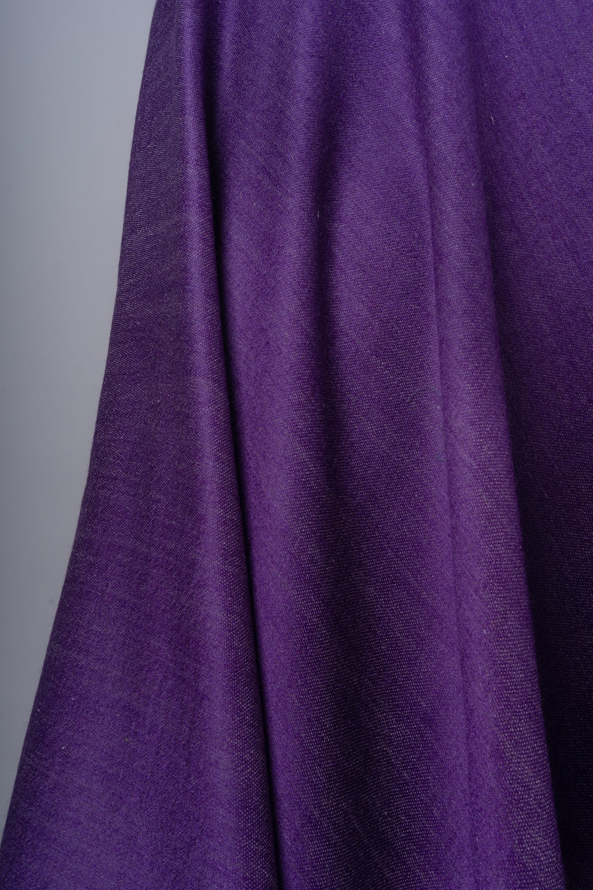 Close-up of soft folds in plain purple Merino wool fabric, showing the fine weave and slight sheen