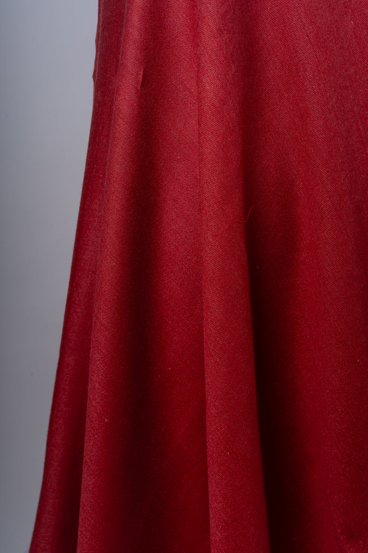 Detail of the crimson stole’s hanging folds and fine woven texture