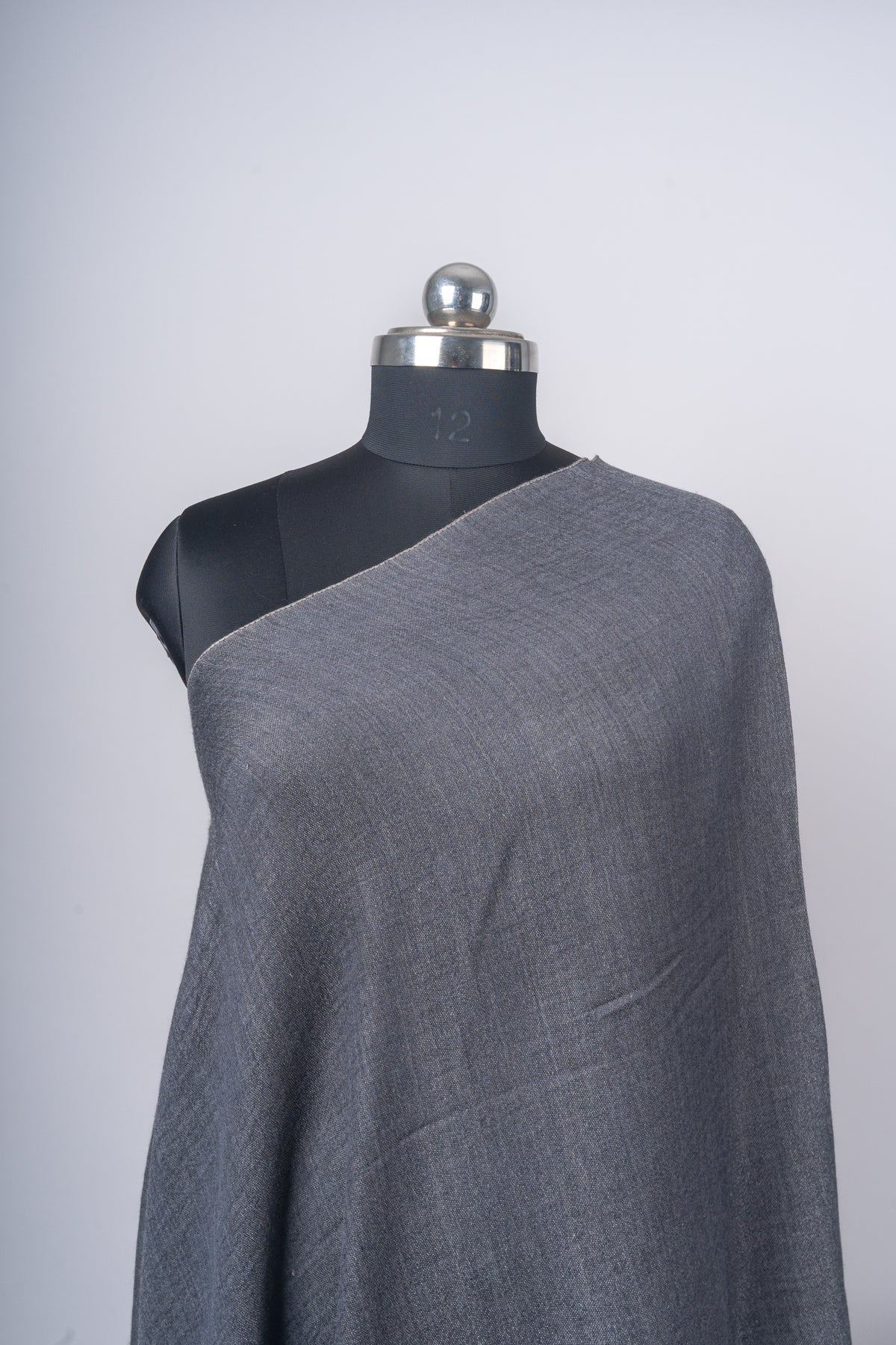 Close-up of the charcoal stole across a mannequin shoulder, showing its fine woven texture and plain edge.