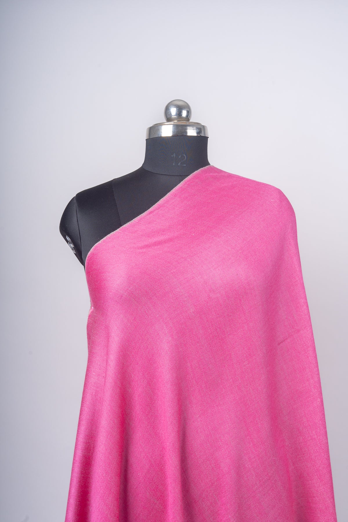Close-up of the candy-pink stole across a mannequin’s shoulder, showing its plain weave and soft folds