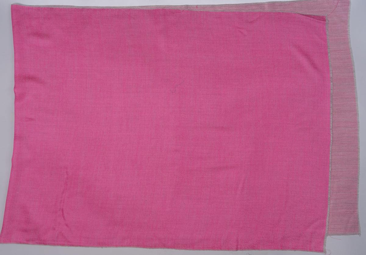 Candy-pink side of a reversible Merino wool stole spread flat, with the pale rose reverse visible around the edges