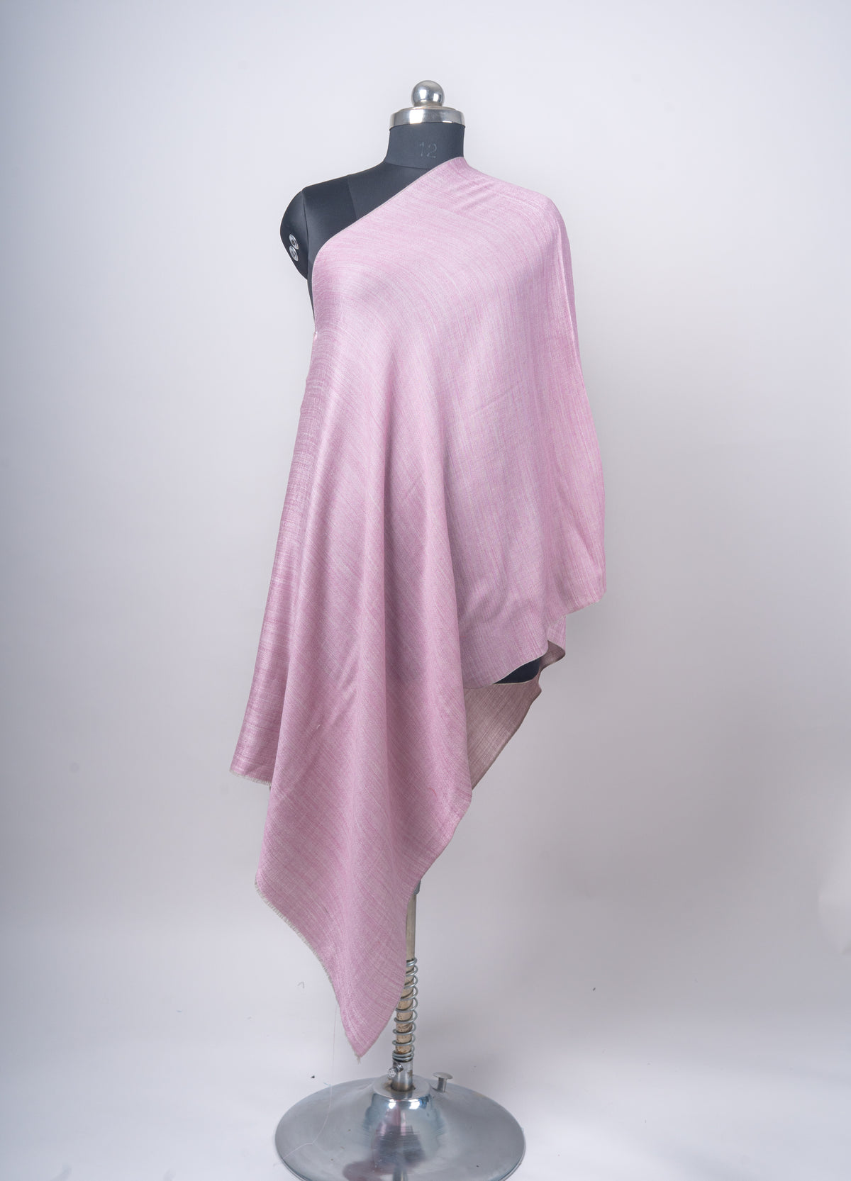 Rose-pink reversible stole hanging in long folds on a mannequin, with a pale mauve-grey edge turned outward