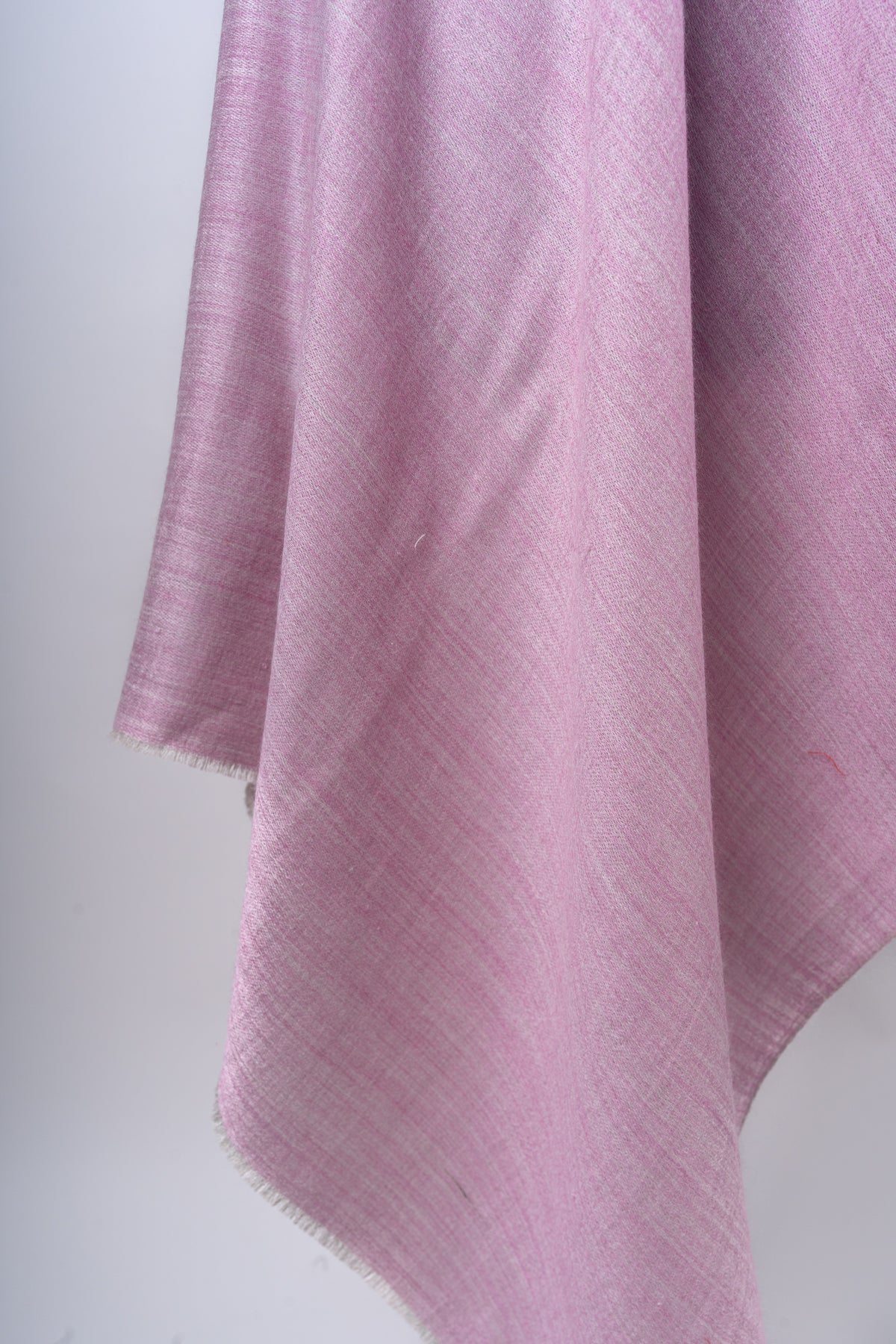 Close-up of rose-pink Merino wool folds and a short fringed edge
