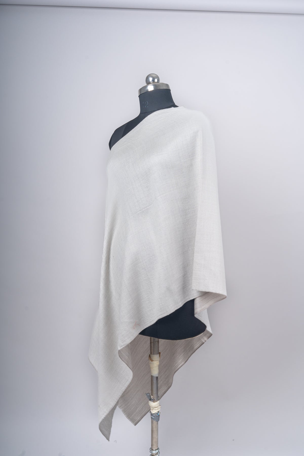 Ivory Merino wool stole draped diagonally over a mannequin, with the taupe reverse visible beneath the lower edge