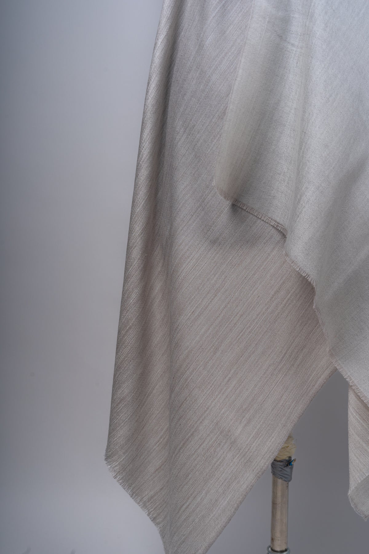 Close view of overlapping ivory and taupe layers of the reversible stole, showing the fine woven texture