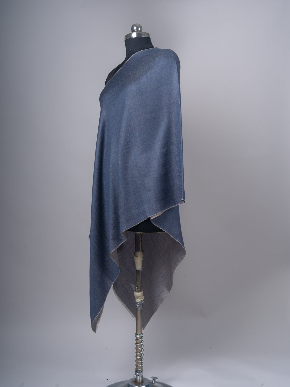 Side view of the draped blue stole showing its contrasting grey underside and softly layered ends.