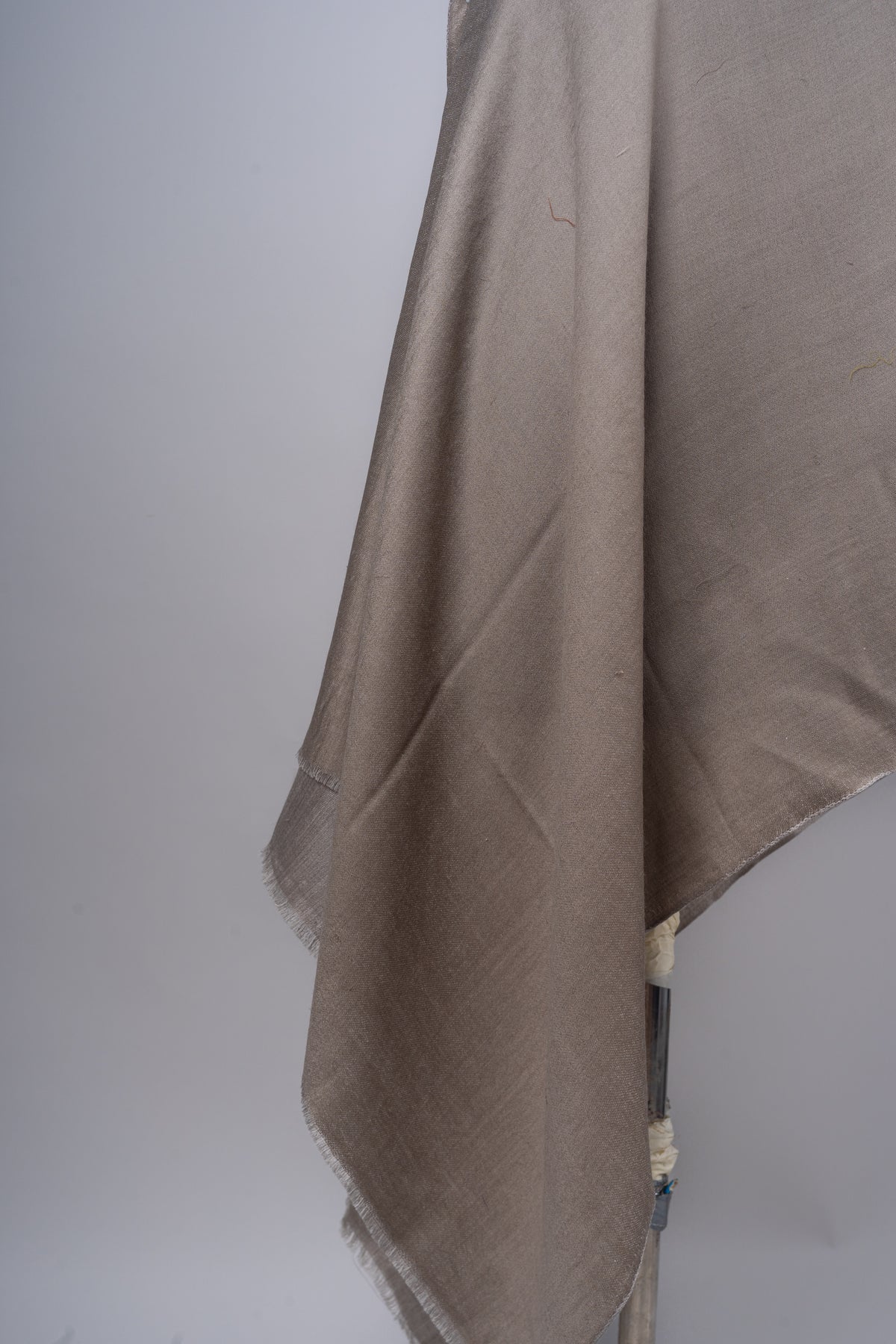 Detail of the taupe stole’s overlapping folds and short fringe along the ends