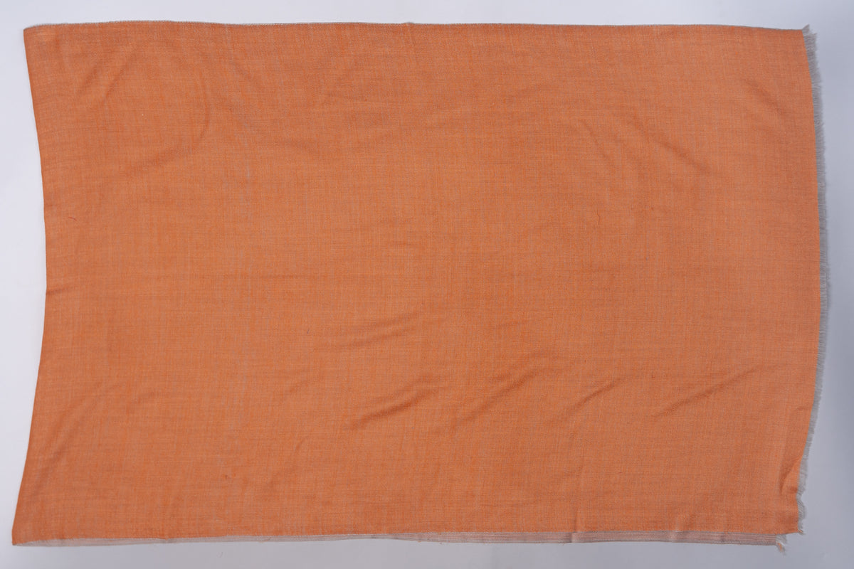 Amber side of a rectangular Merino wool stole laid flat, showing its plain weave, light creases and short fringe