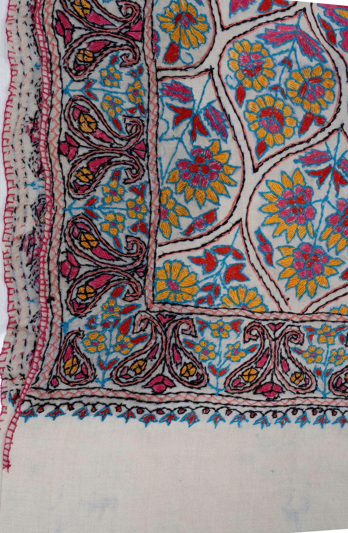 Ivory stole corner with blue, yellow and pink Sozni flowers inside dark outlines beside a detailed paisley border