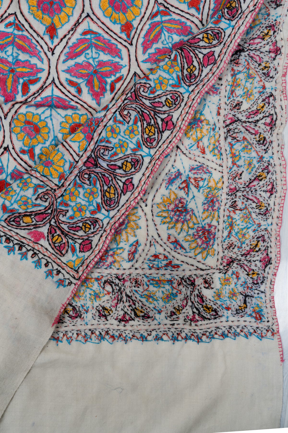 Folded ivory stole corner showing both sides of colourful Sozni floral lattice embroidery and paisley borders