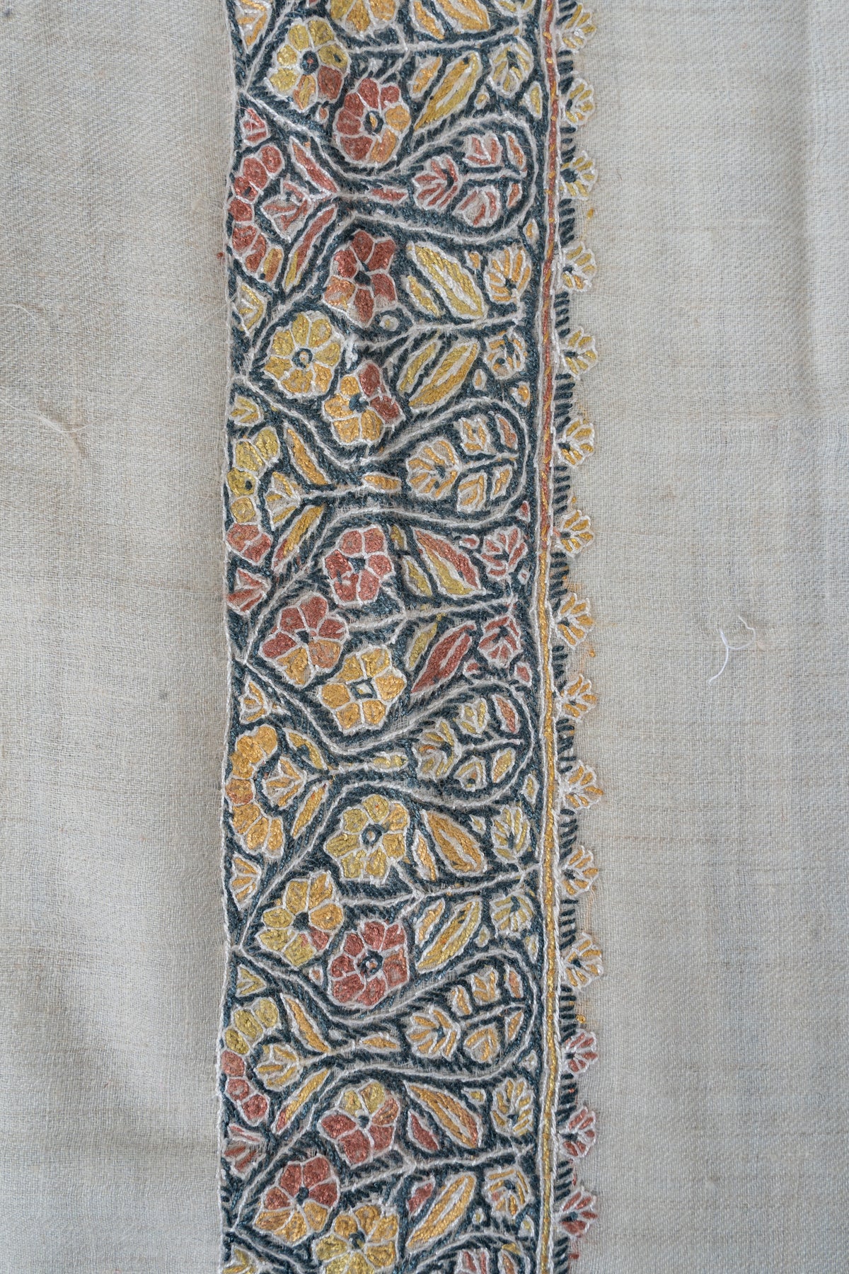 Close-up of the ivory rumal's blue floral border with coral and yellow flowers