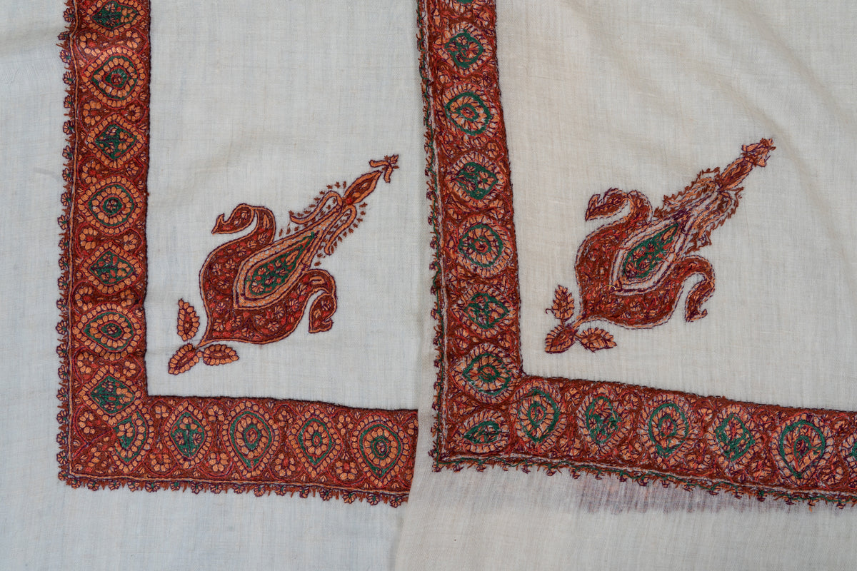 Folded ivory rumal showing both sides of rust-red and green corner paisleys and floral medallion borders