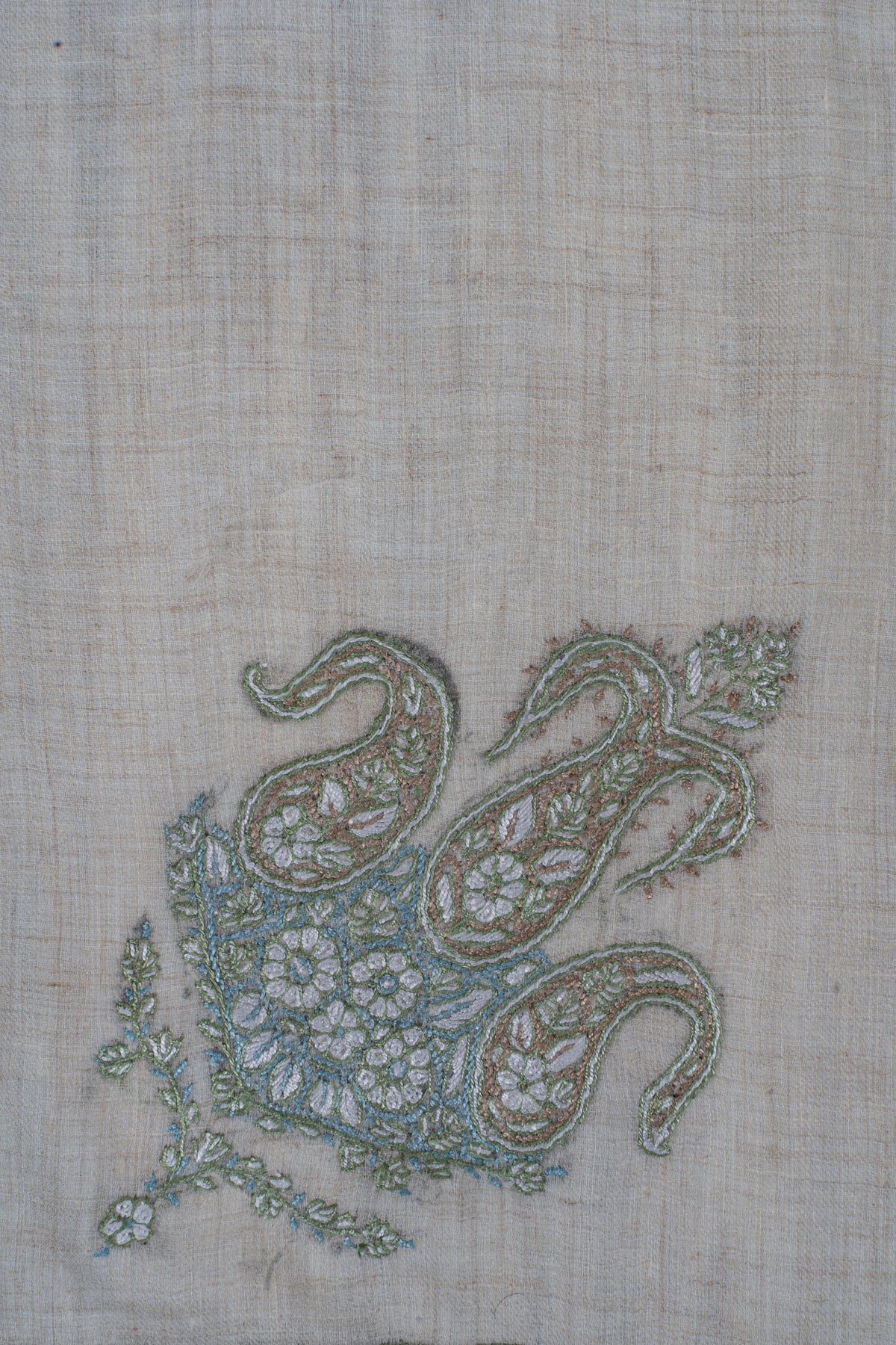 Close-up of the rumal's three curling paisleys with pale flowers and sage-green outlines