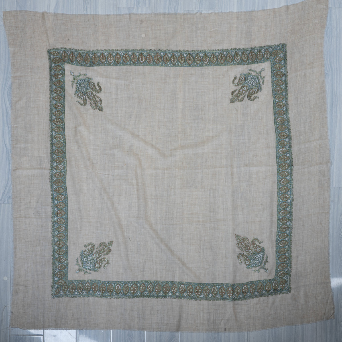 Pale beige cashmere rumal laid flat with a square sage-aqua border and four matching corner motifs