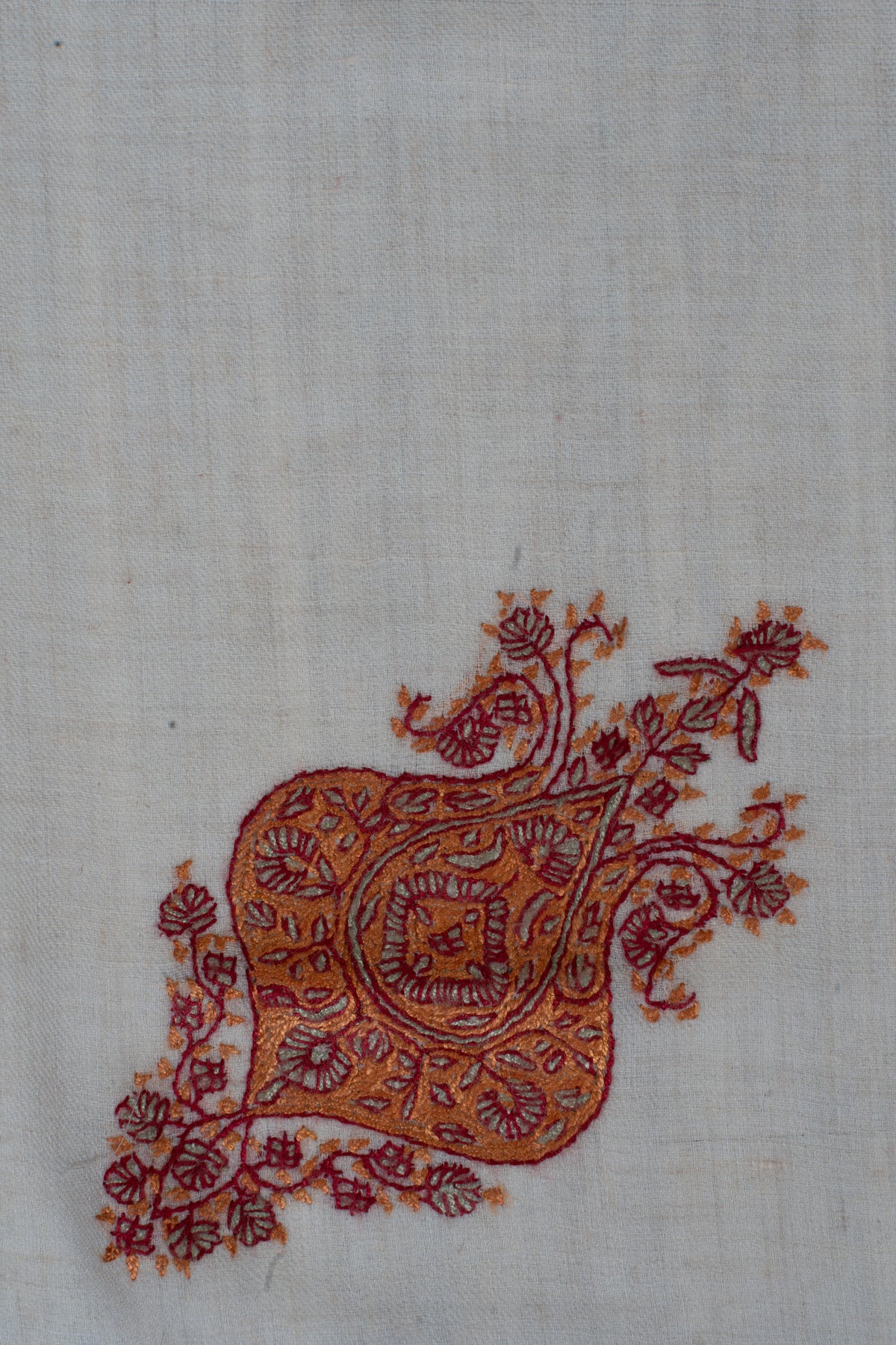 Close-up of a burnt-orange Sozni floral motif with a teardrop centre, dark red outlines and leafy sprays on ivory fabric