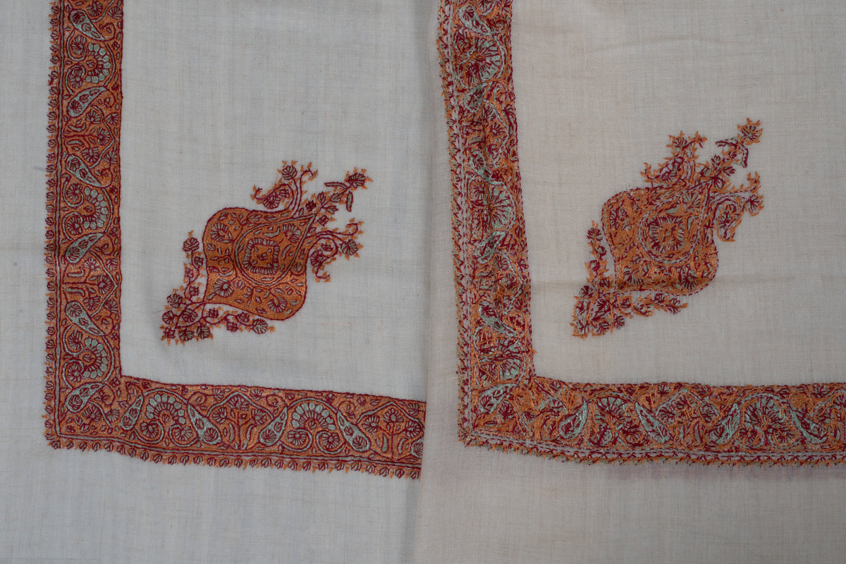 Overlapping ivory rumal corners showing both sides of burnt-orange floral motifs and copper and sage Sozni borders