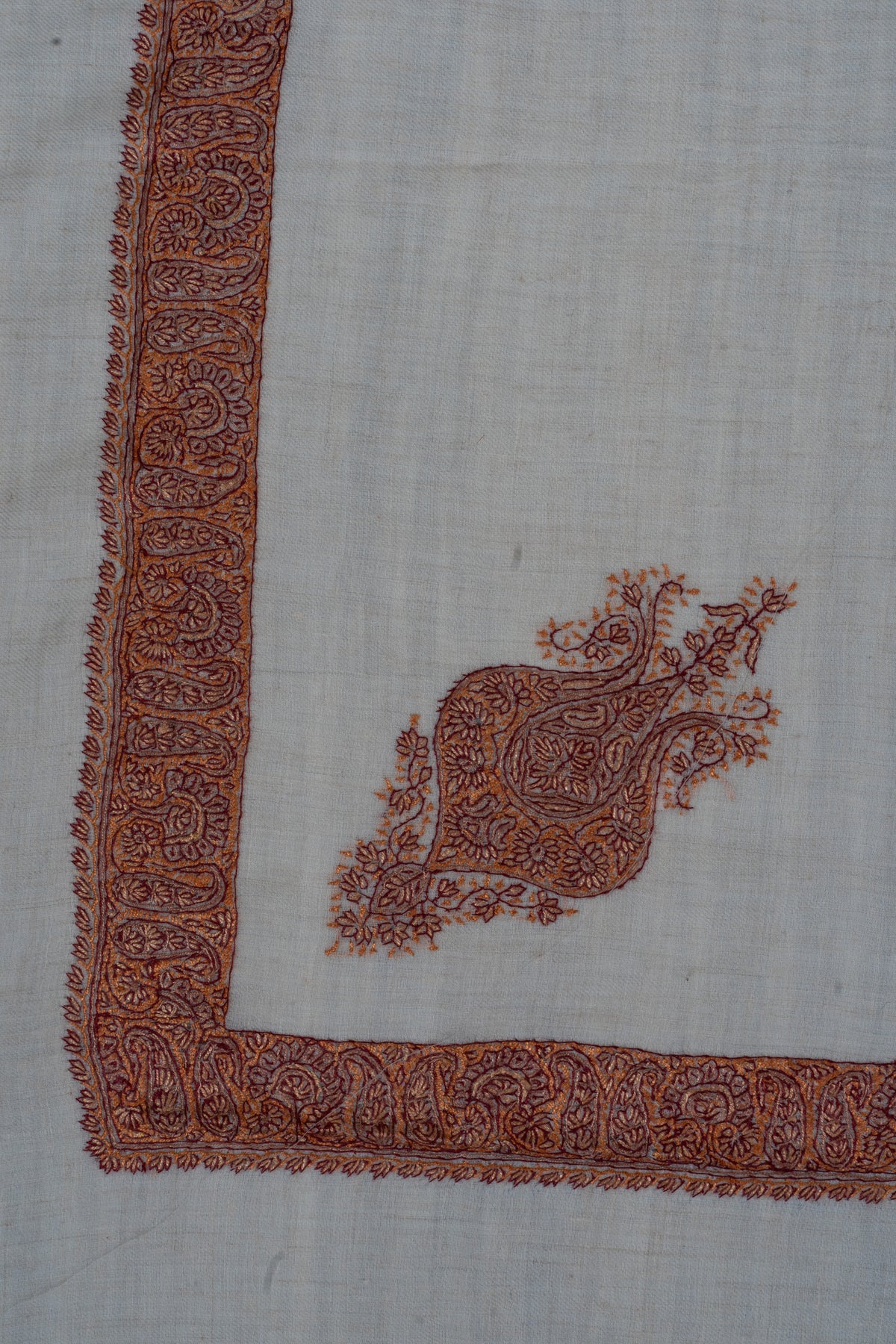 Cream rumal corner with copper and rust Sozni paisley borders and an ornate floral motif