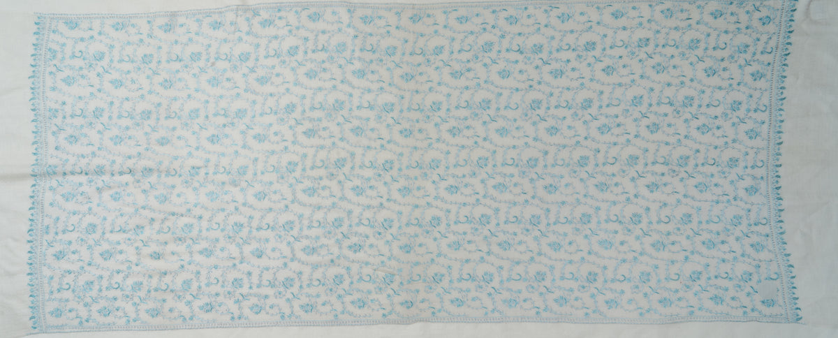 Entire white stole laid flat, with an all-over pale blue floral-vine pattern framed by narrow embroidered borders.