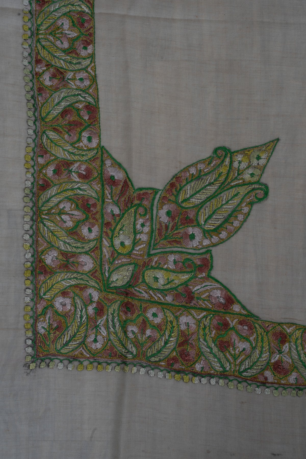 Pale beige rumal corner with a large green-outlined leaf motif joined to a rose, gold and green Sozni border