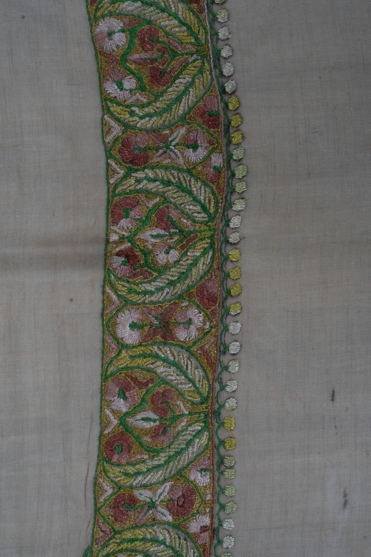Close-up of a green and rose Sozni rumal border with large curling leaves, small flowers and pale gold accents