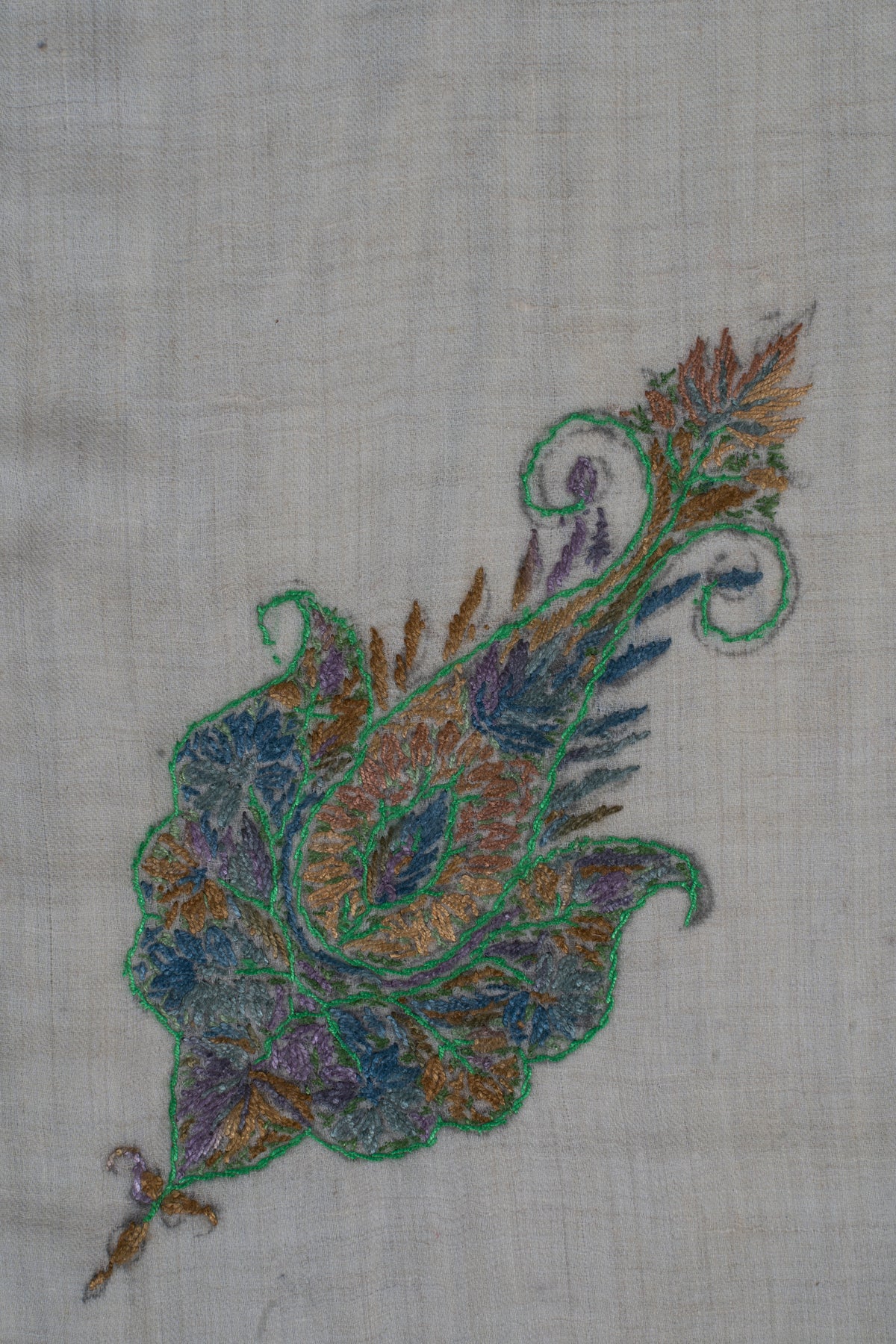 Close-up of the rumal's smaller curled motif with green outlines, blue leaves and gold accents