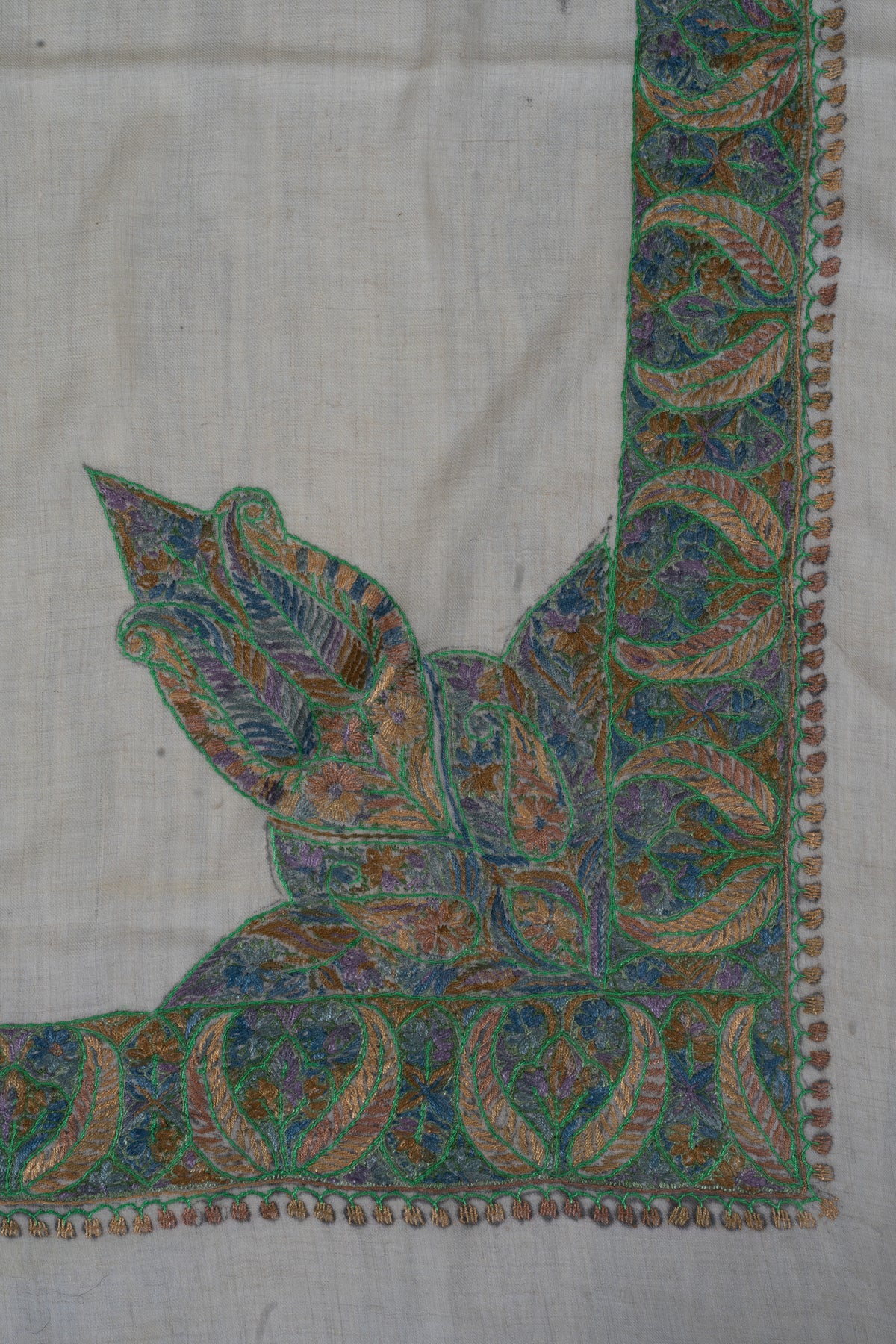 Ivory rumal corner with a large pointed leaf design extending from the green and blue border