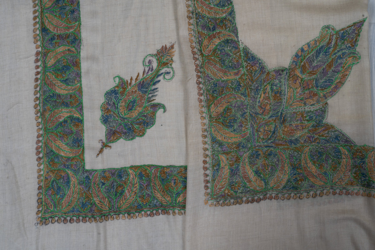 Overlapping ivory rumal corners showing the smaller floral motif beside the large pointed leaf design