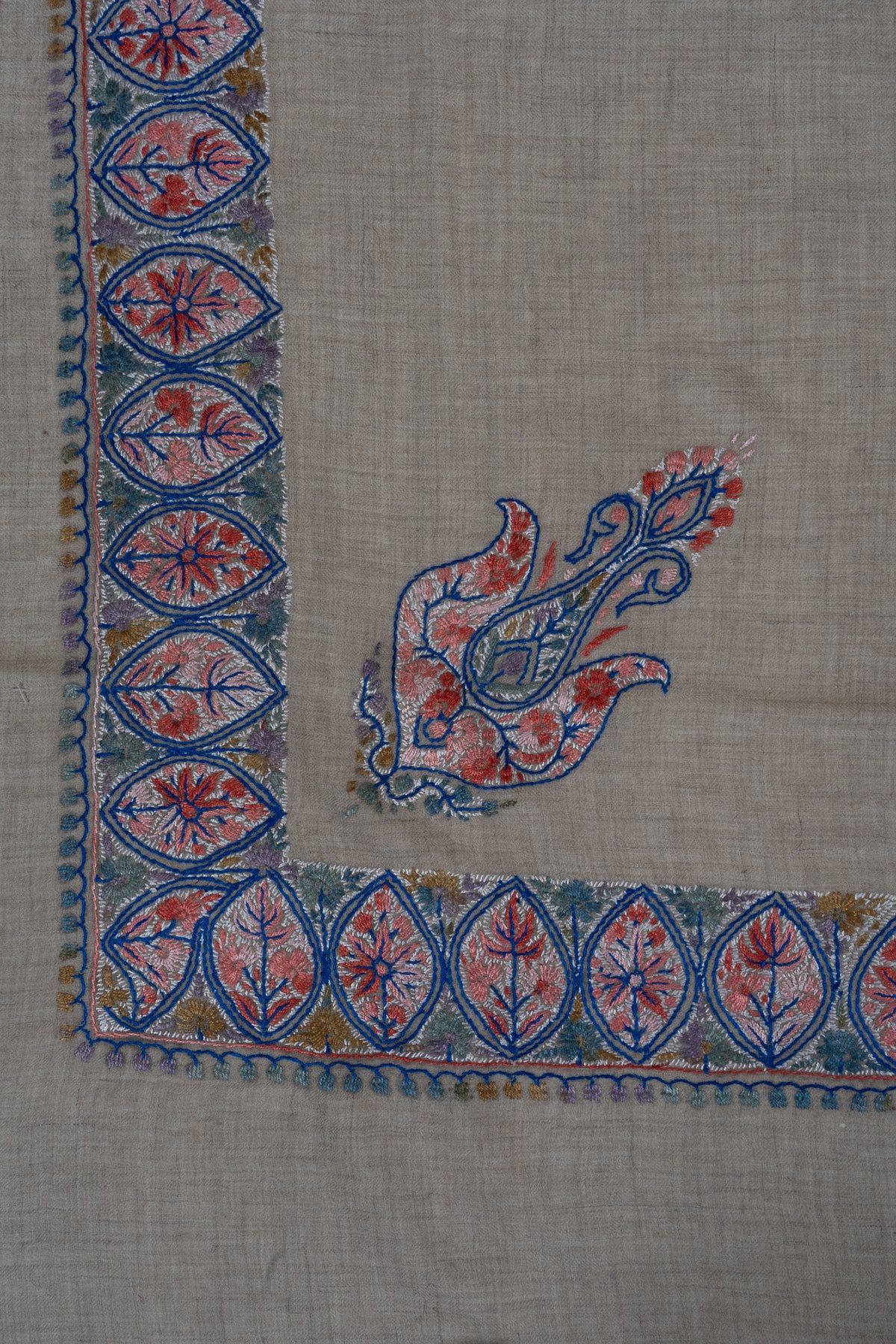 Beige rumal corner with a small coral and blue Sozni paisley inside a narrow leaf medallion border