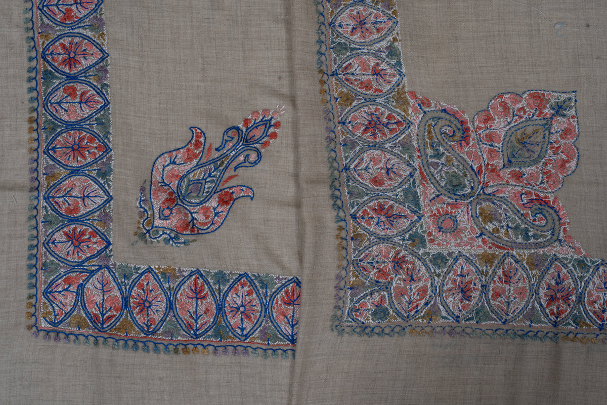 Folded beige rumal showing both sides of coral and blue Sozni borders with large and small corner motifs