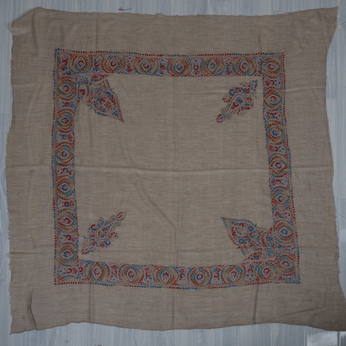 Taupe cashmere rumal laid flat, with crimson-blue borders, two large pointed designs and two smaller corner motifs