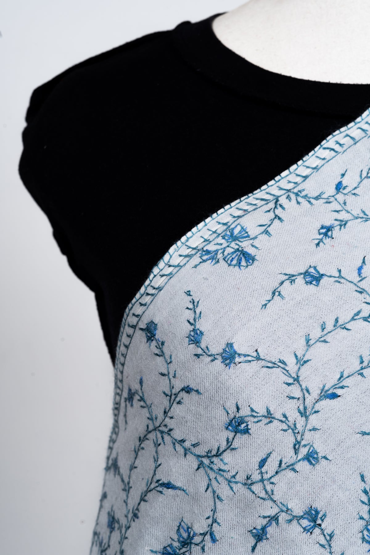 Close-up of the ivory stole’s shoulder, showing small blue flowers, fine leafy stems and narrow embroidered edging