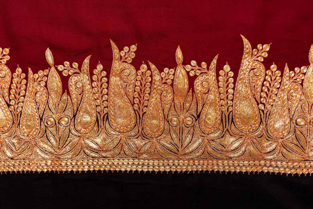 Close-up of the shawl end band with tall gold-coloured paisleys, leafy stems and buds above the black panel.