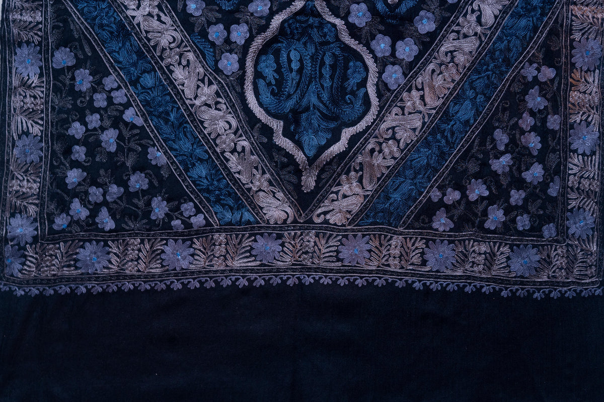 Flat end detail of the black stole with blue flowers and a pointed floral panel above a silver-toned border