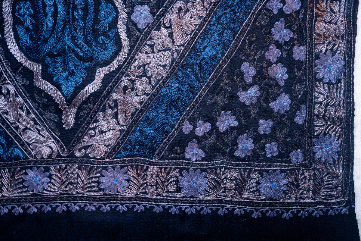 Corner detail of blue and silver-toned Aari flowers and leaves along intersecting borders on the black stole