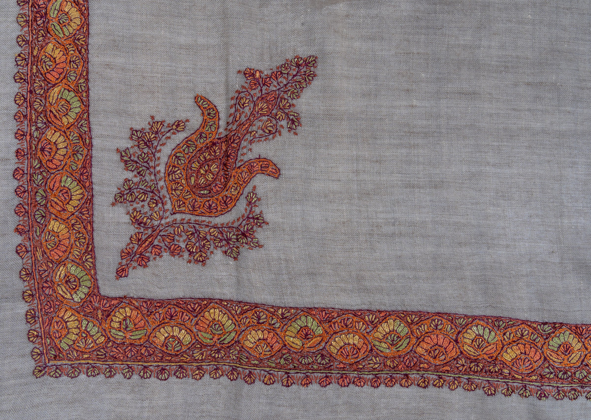 Corner of a taupe rumal with a saffron and crimson paisley inside a floral Sozni border with green accents